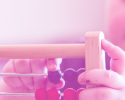 TBDSSAB Child Care and Early Years Programs header image: a closeup of a young child playing with a colourful abacus / wooden bead toy.