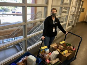 Michelle Kolobutin stands behind two full carts of groceries in the lobby of NorWest Community Health Centre.