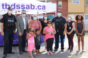 TBDSSAB staff, tenants, and guests from the Thunder Bay Police Community Oriented Response unit standing in the WIndsor Street townhomes courtyard