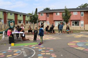 Attendees at Windsor street participating in children's activities and sitting on benches enjoying their lunch.