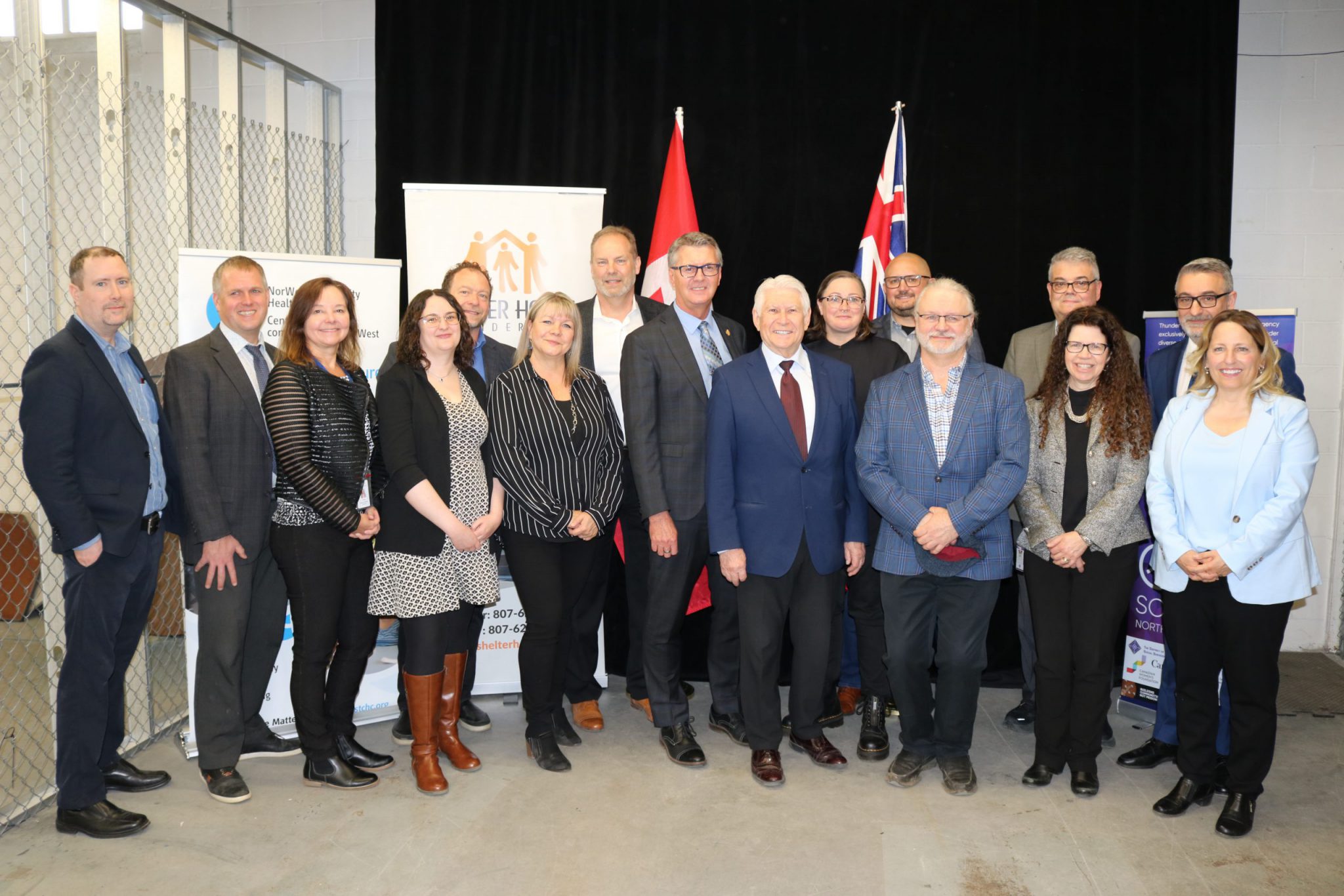 Group photo from April 26, 2024 media event in Thunder Bay, with Minister Calandra (back right), MPP Holland, Mayor Boshcoff, representatives of TBDSSAB Board and administration, and all four funded initiatives.